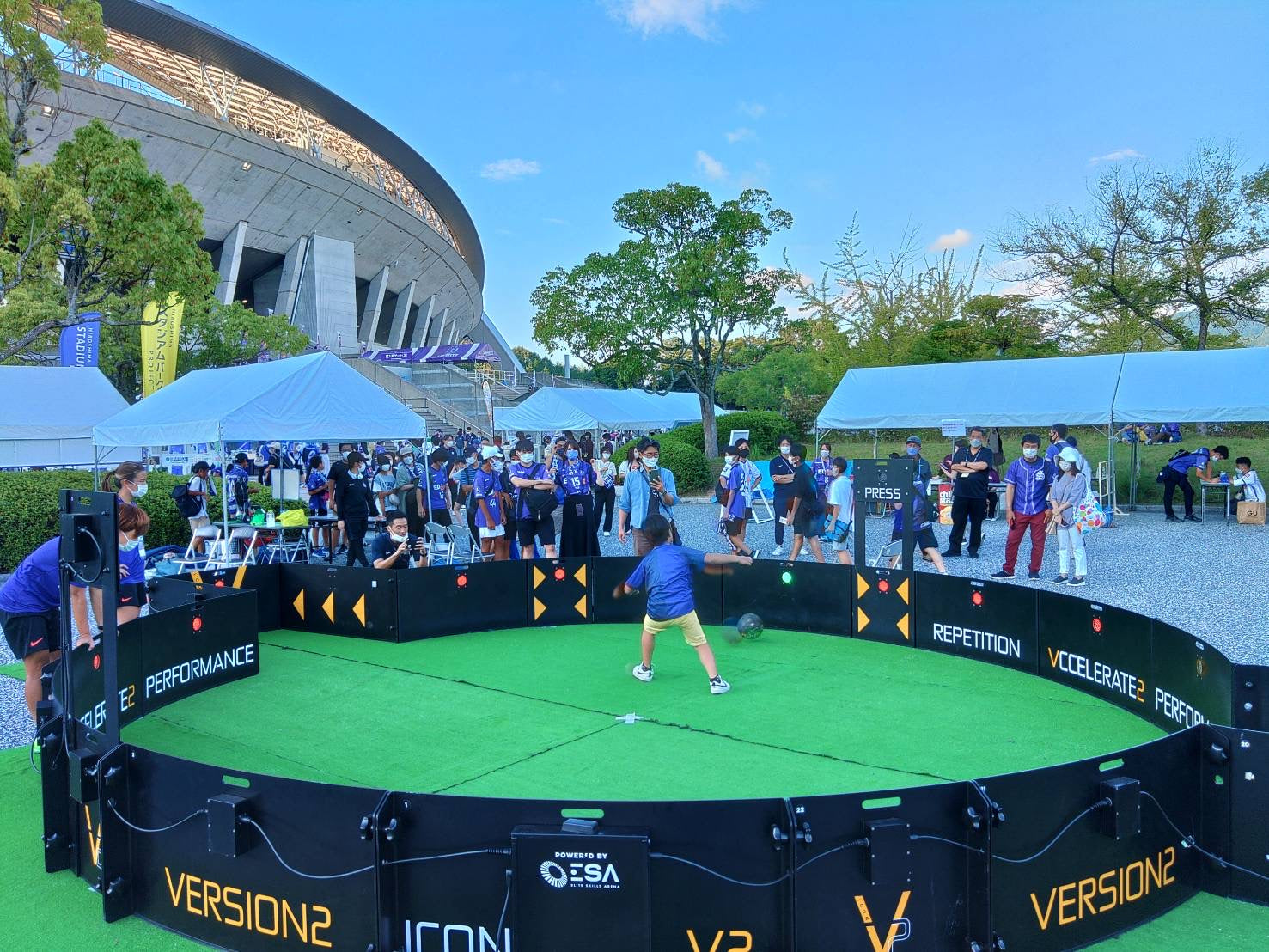 boy kicking football inside acura icon v2 with green astro inside the arena and crowd watching