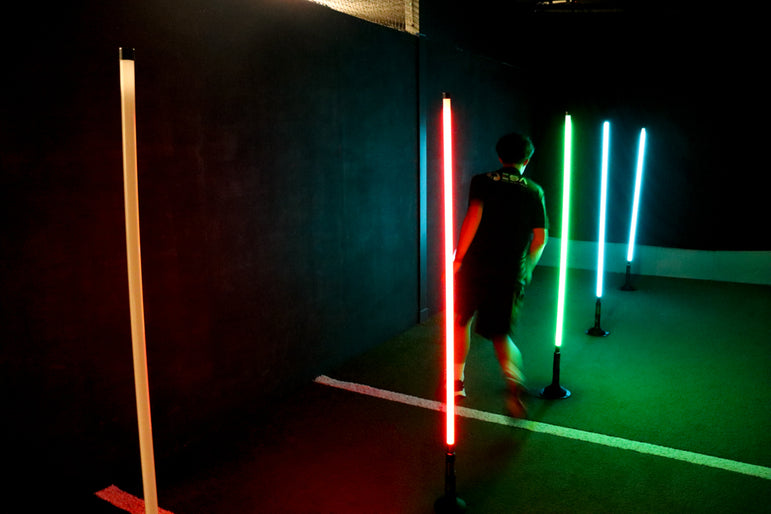 man dribbling football through acura elite training lane (dribble) in dark facility with neon lights