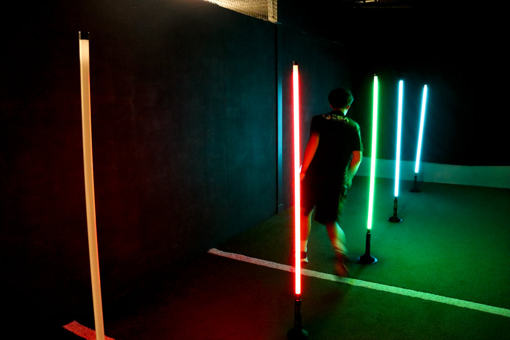 man dribbling football through acura elite training lane (dribble) in dark facility with neon lights