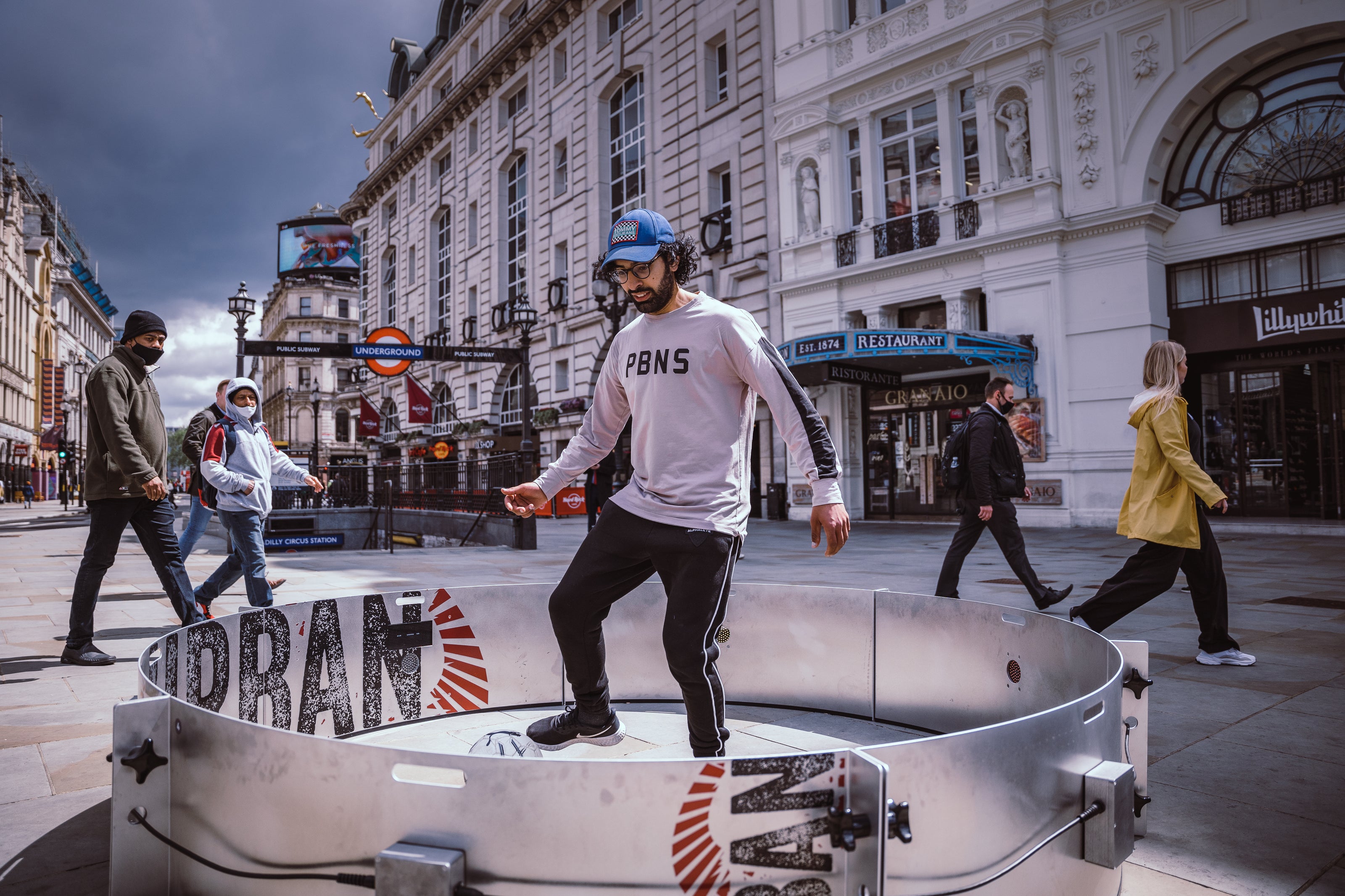 Man in Picadilly outside london underground using football acura icon fast feet with urban branding