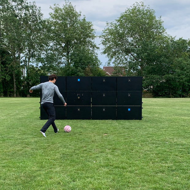 man kicking football at acura elite precision wall 12 panel outside on field
