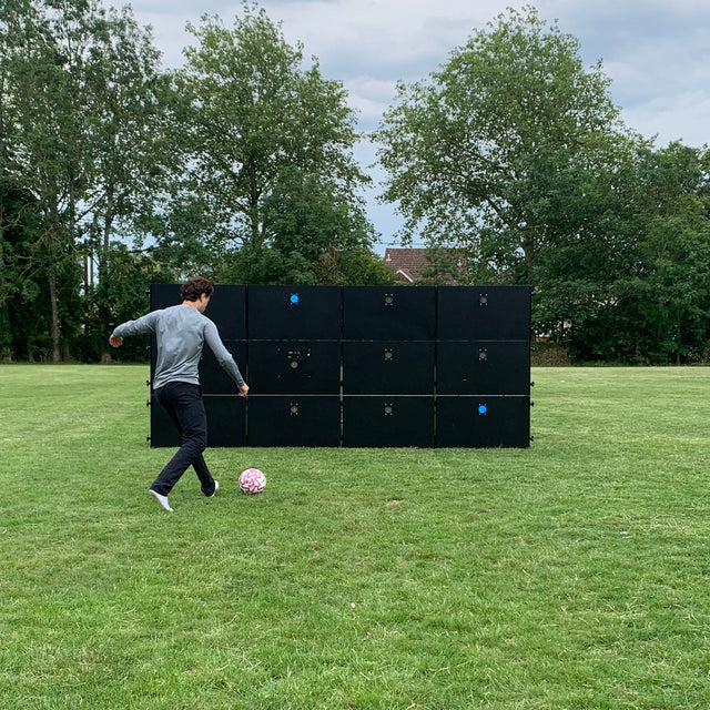 man kicking football at acura elite precision wall 12 panel outside on field