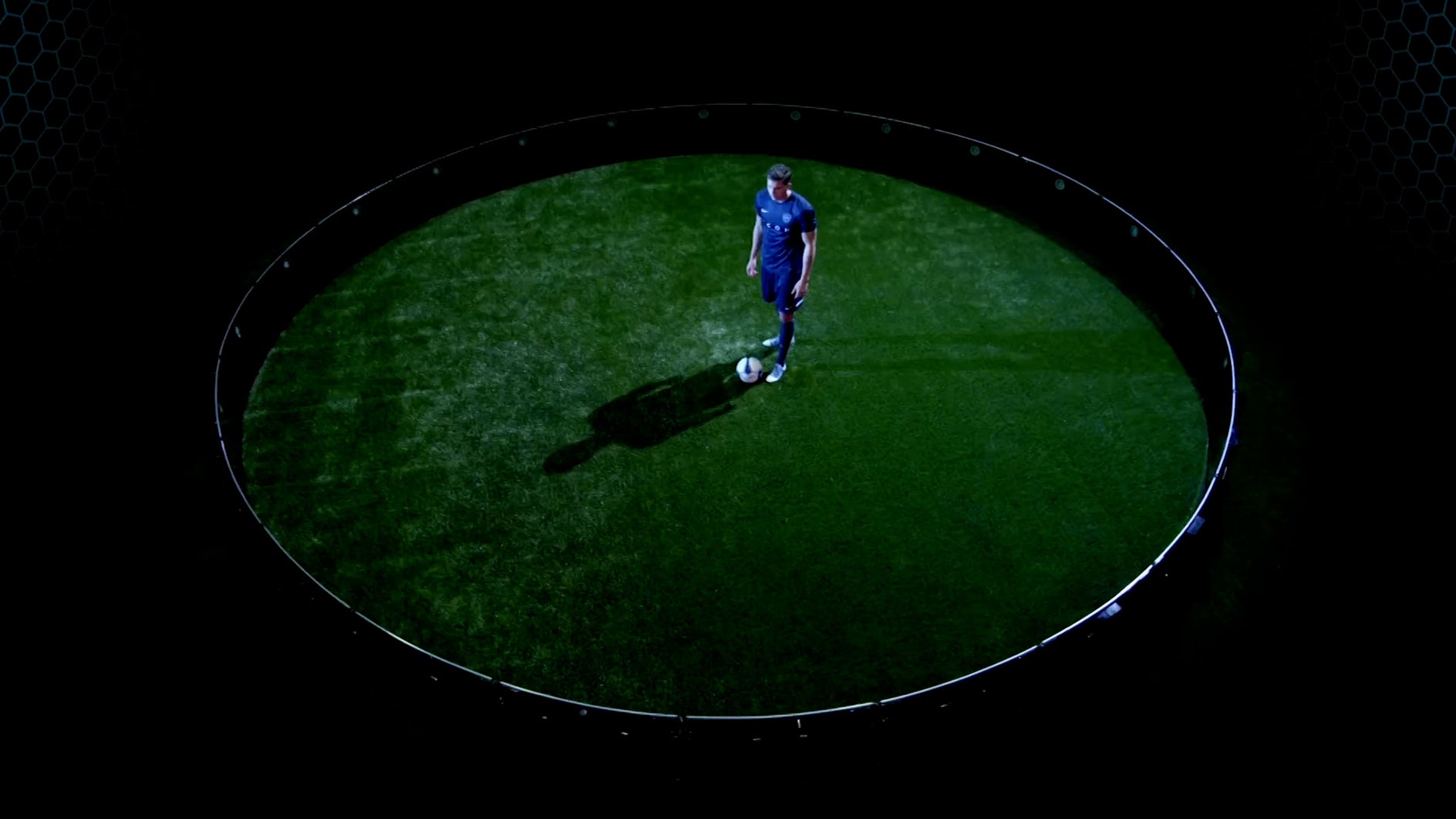 A thumbnail of a soccer/football player in a blue uniform stands on a green field inside a ICON Arena, casting a long shadow against a dark background.