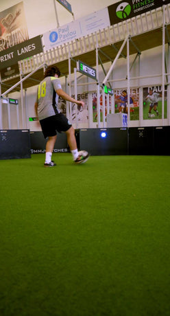 Person playing football using acura elite icon v2 on a green indoor court 