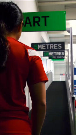 a girl wearing a red football kit standing in front of an acura elite training lane (sprint) inside training faclity