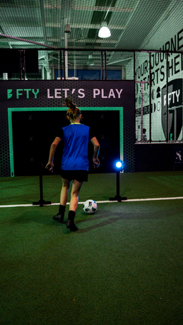 Girl running through acura wireless circuit gate module inside sports facility wearing blue bib