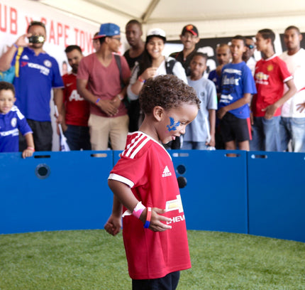 smiling boy standing inside icon arena with blue panels and crowd watching