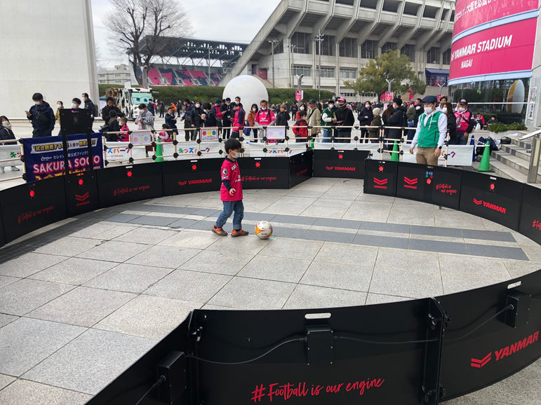 Child playing with a ball in front of a large crowd using acura icon v2