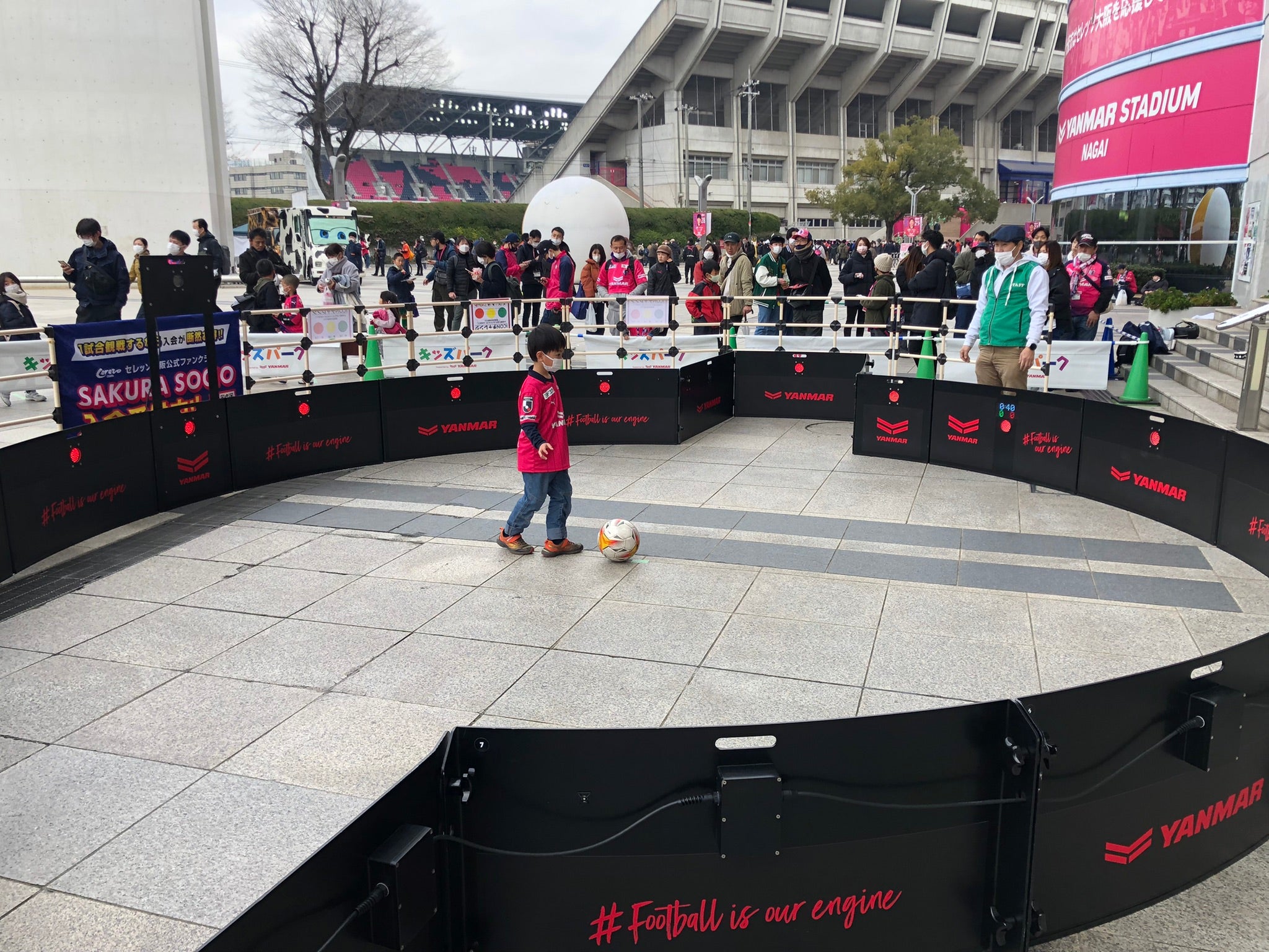 Child playing with a ball in front of a large crowd using acura icon v2