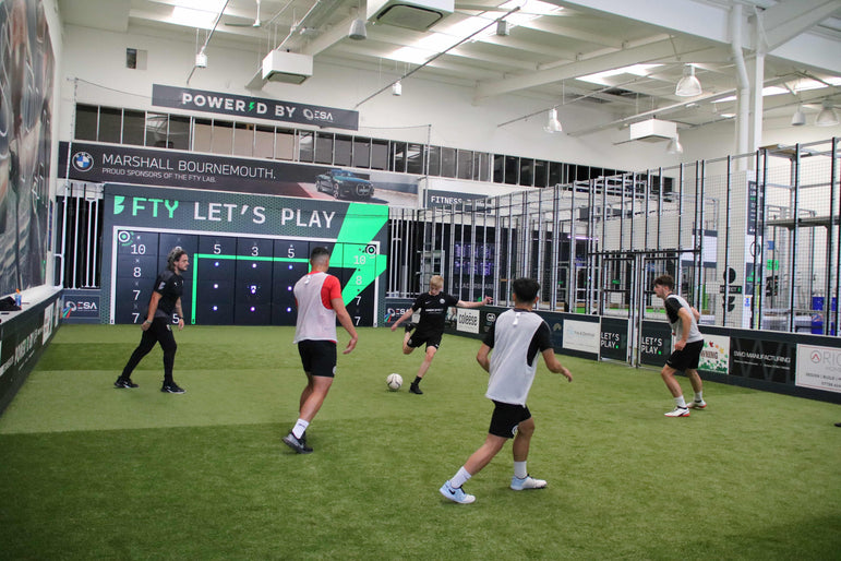 boys in football kits playing football on smart pitch with acura 28-panel precision wall
