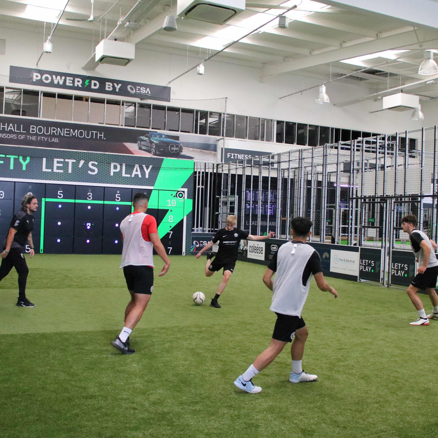 boys in football kits playing football on smart pitch with acura 28-panel precision wall