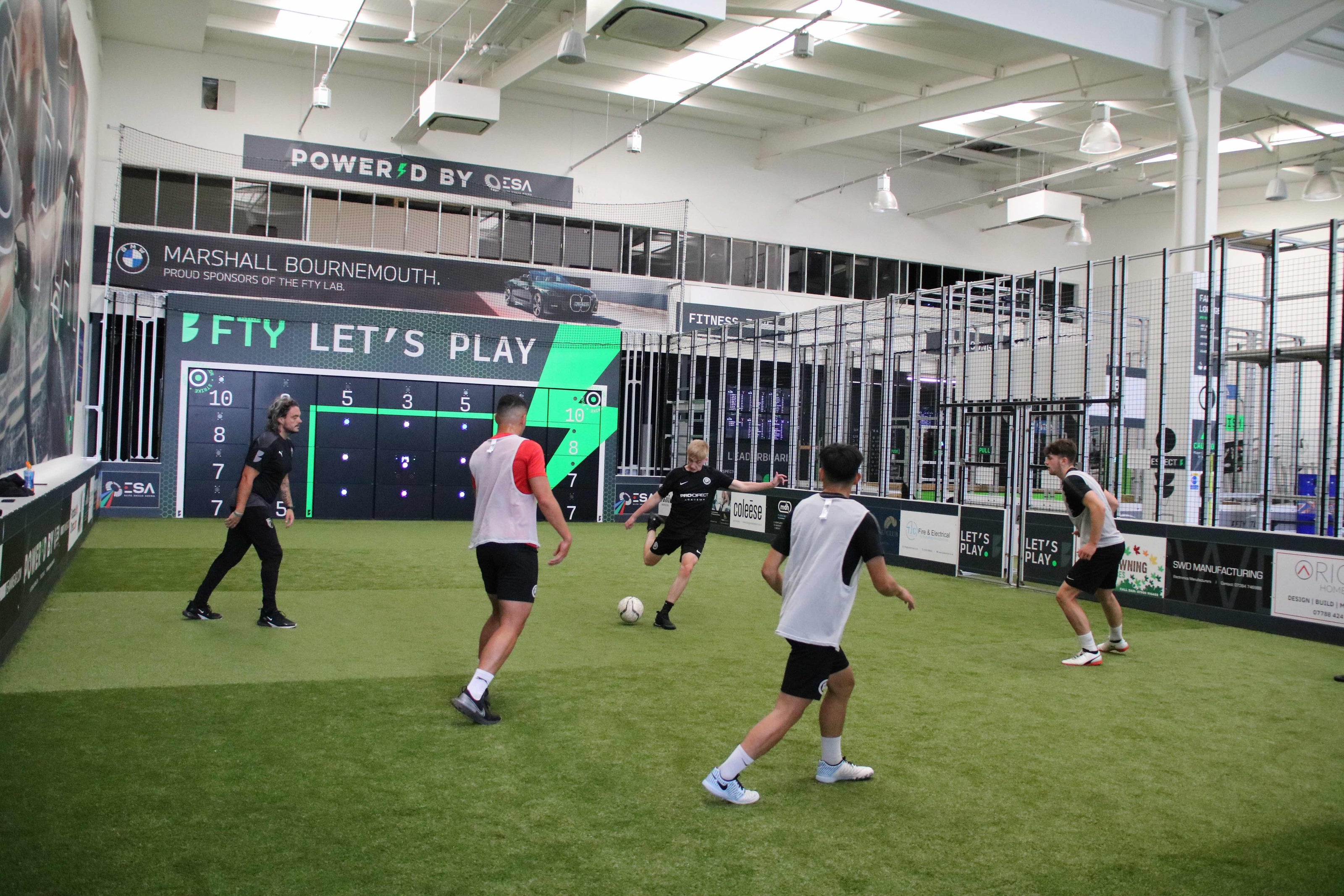 boys in football kits playing football on smart pitch with acura 28-panel precision wall