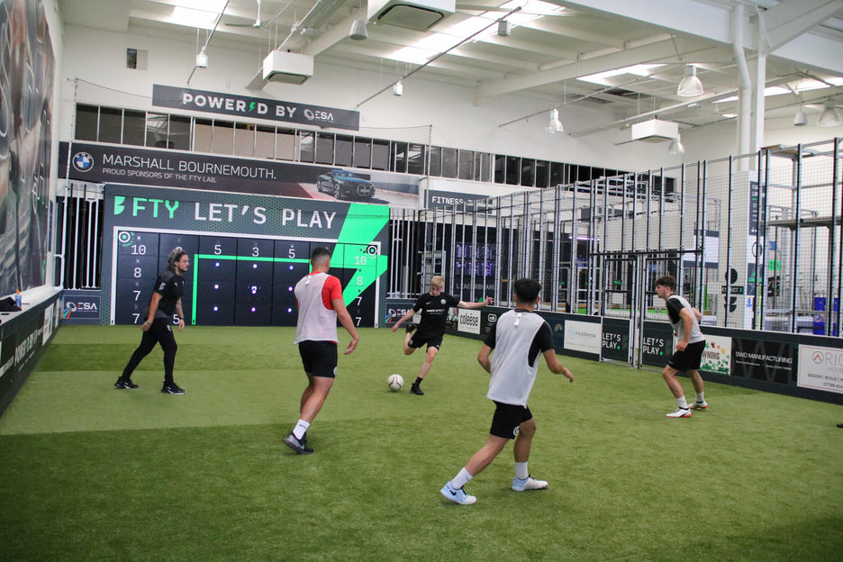 boys in football kits playing football on smart pitch with acura 28-panel precision wall
