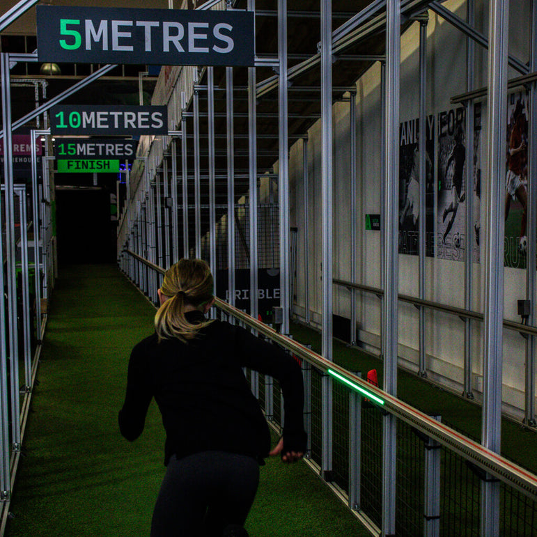 girl in a black training outfit running down sprint lane with 5 metre signs above