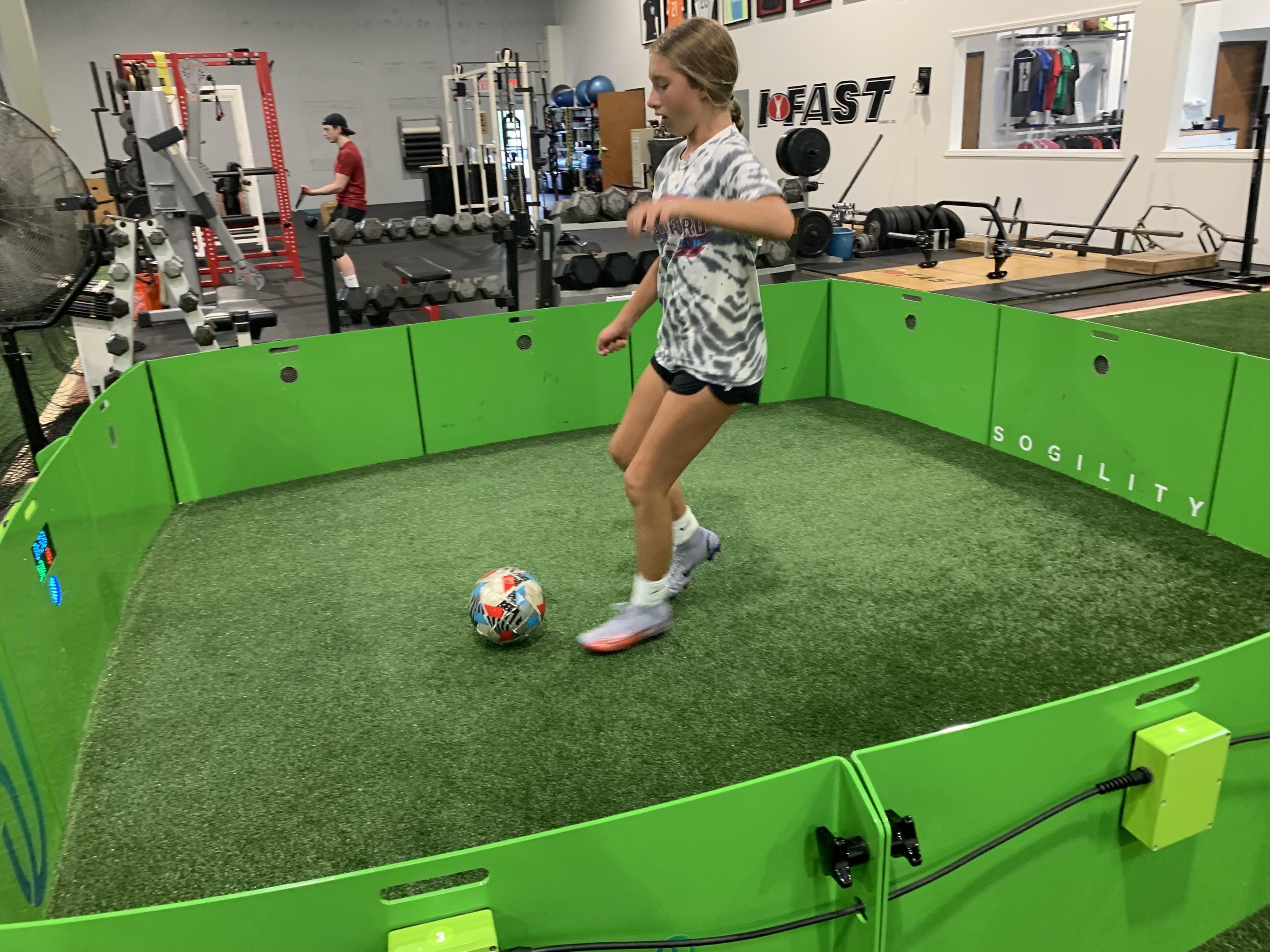 girl using icon cube inside gym dribbling football