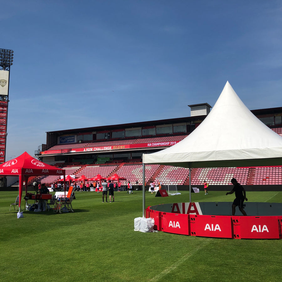 Tents and equipment on a sports field with stadium in the background