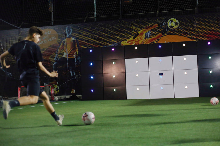man kicking football at 29-panel branded acura 28-panel precision wall with 9 white panels