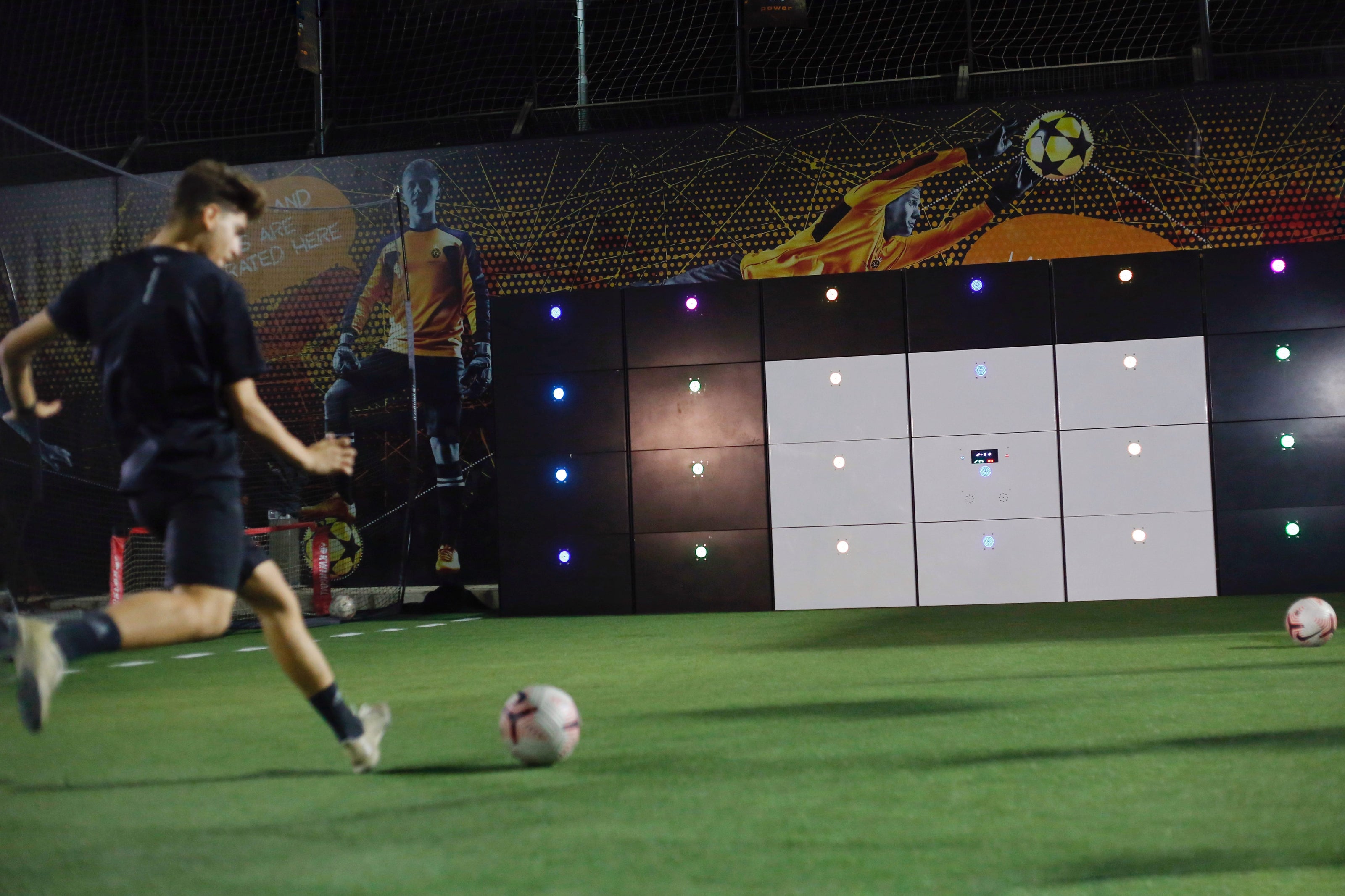 man kicking football at 29-panel branded acura 28-panel precision wall with 9 white panels