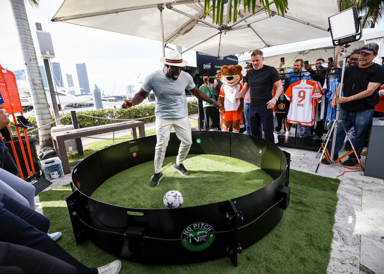 Man dribbling football inside acura icon fast feet with camera crew and spectators