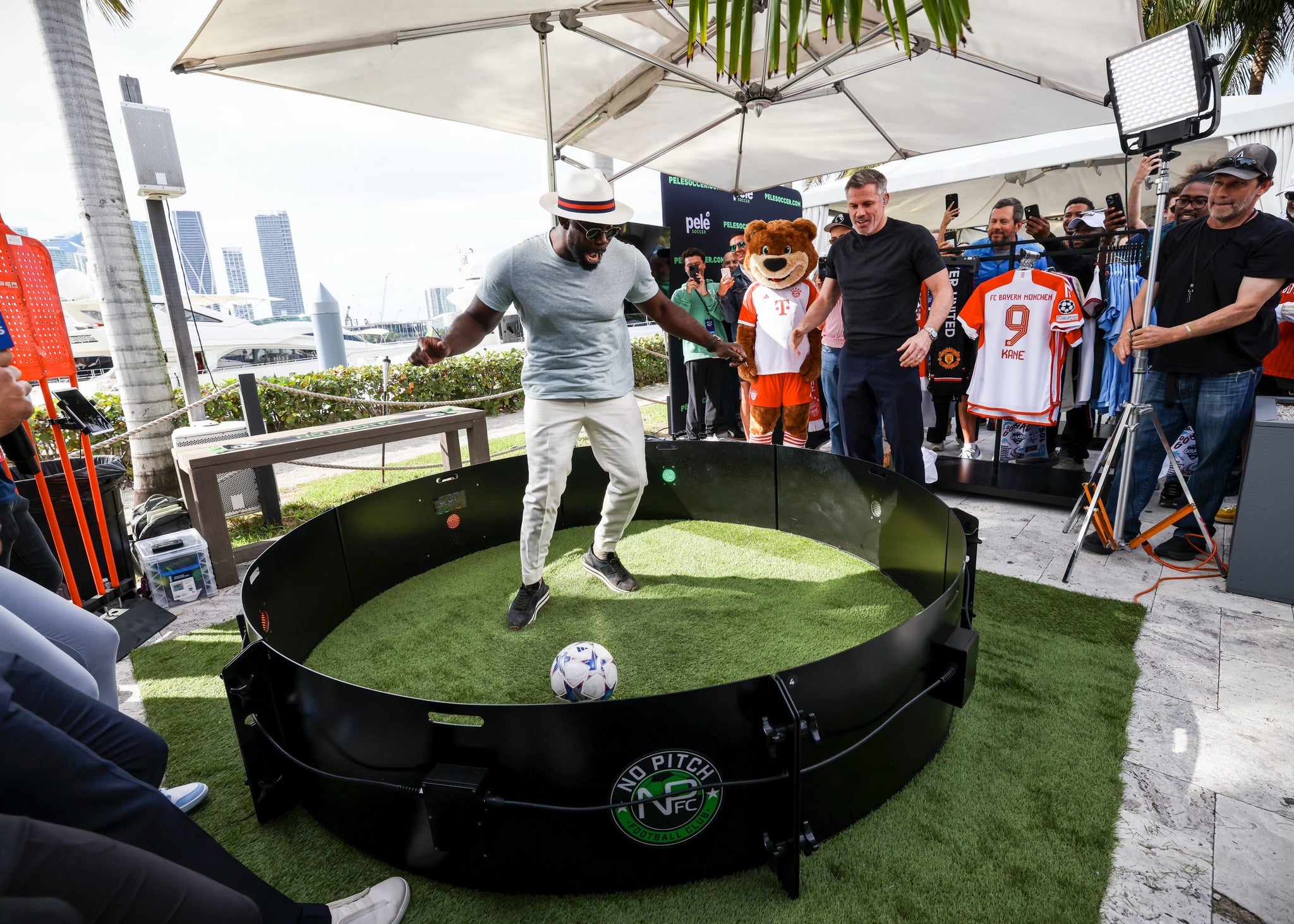 Man dribbling football inside acura icon fast feet with camera crew and spectators
