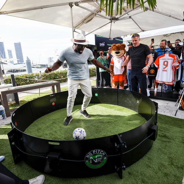 Man dribbling football inside acura icon fast feet with camera crew and spectators