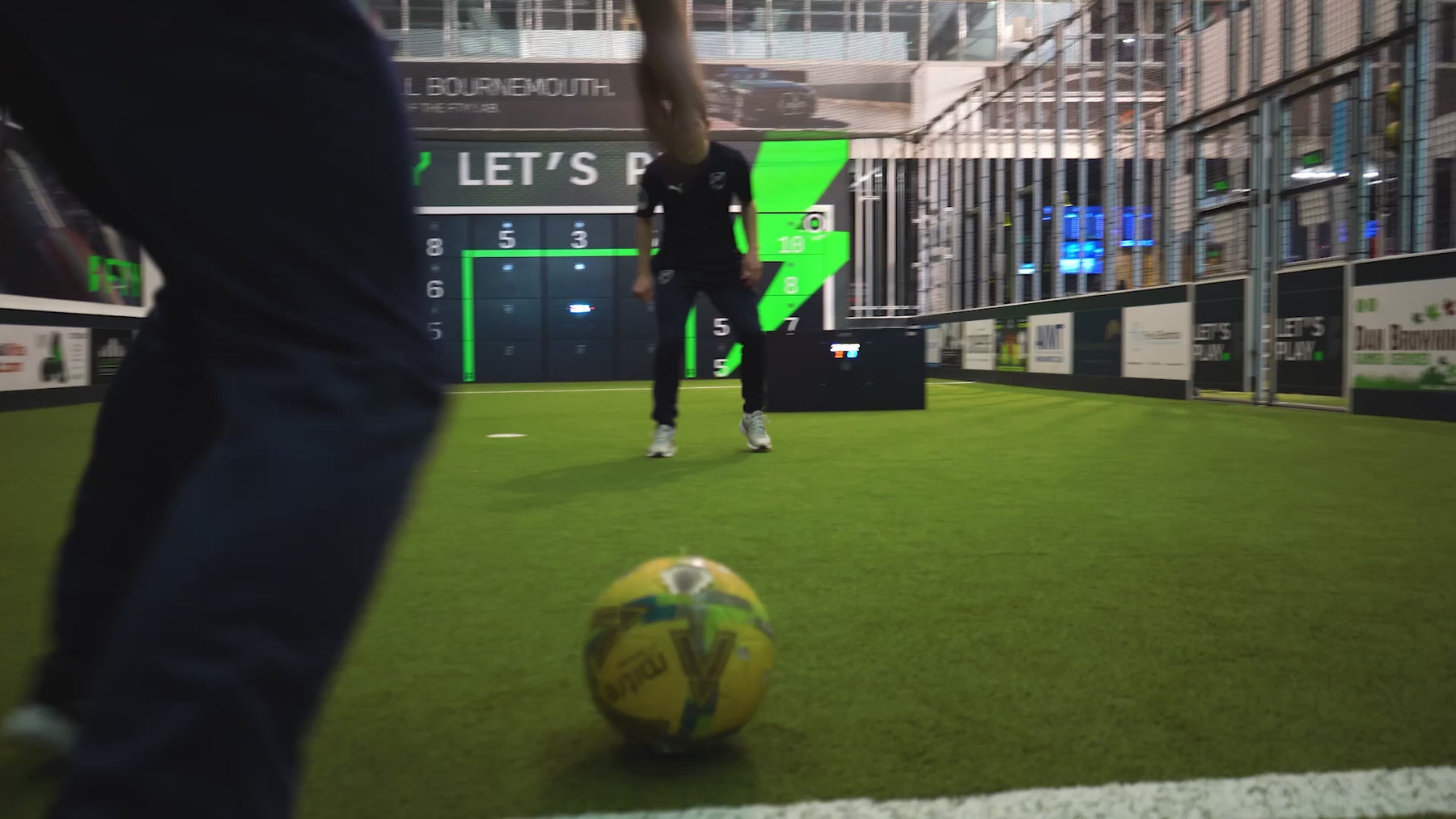 video of man preparing to kick ball past opponent at Acura elite precision wall 28 panel inside training facility on astro turf demonstrating 4 court game mode