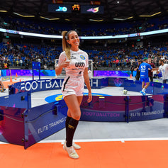 woman posing beside acura elite icon v2 equipment in a sports arena