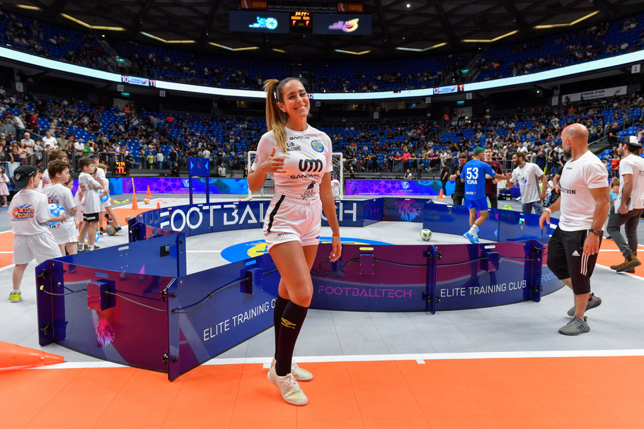 woman posing beside acura elite icon v2 equipment in a sports arena